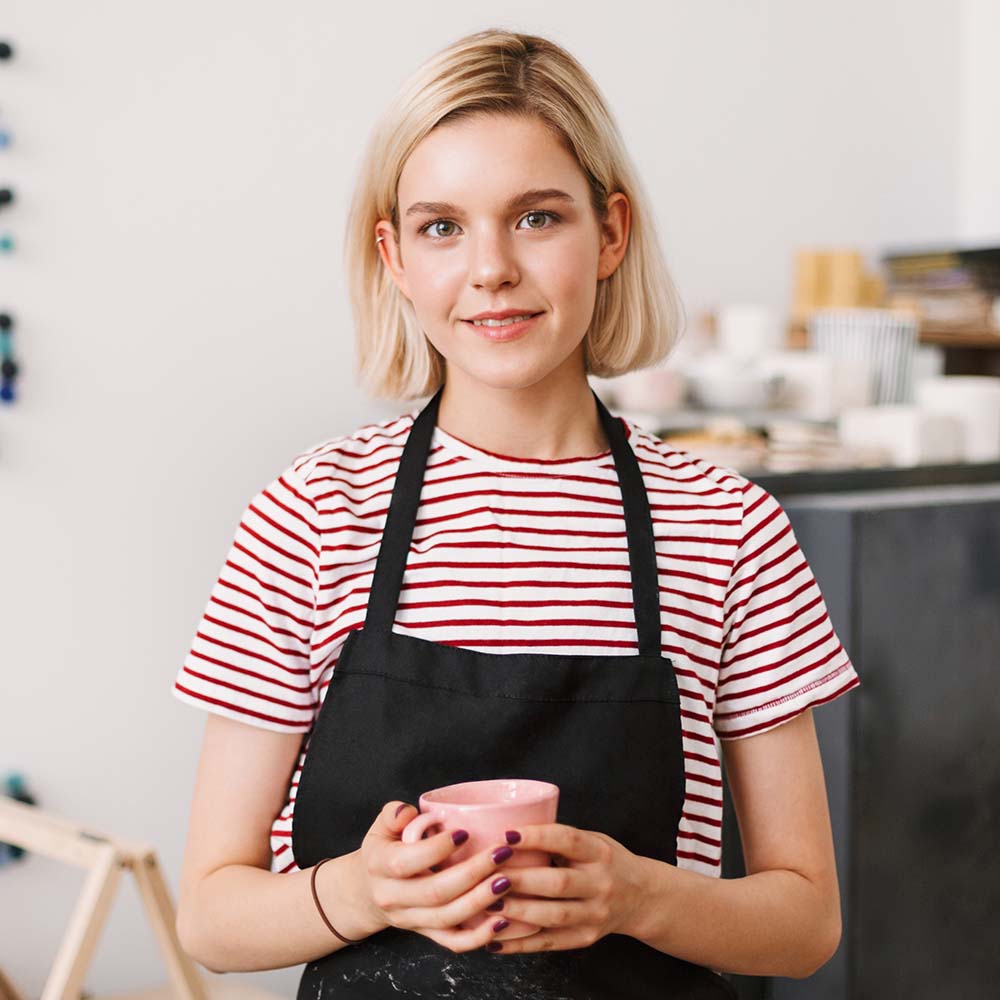 beautiful-girl-in-black-apron-holding-handmade-mug-7JESGBY.jpg